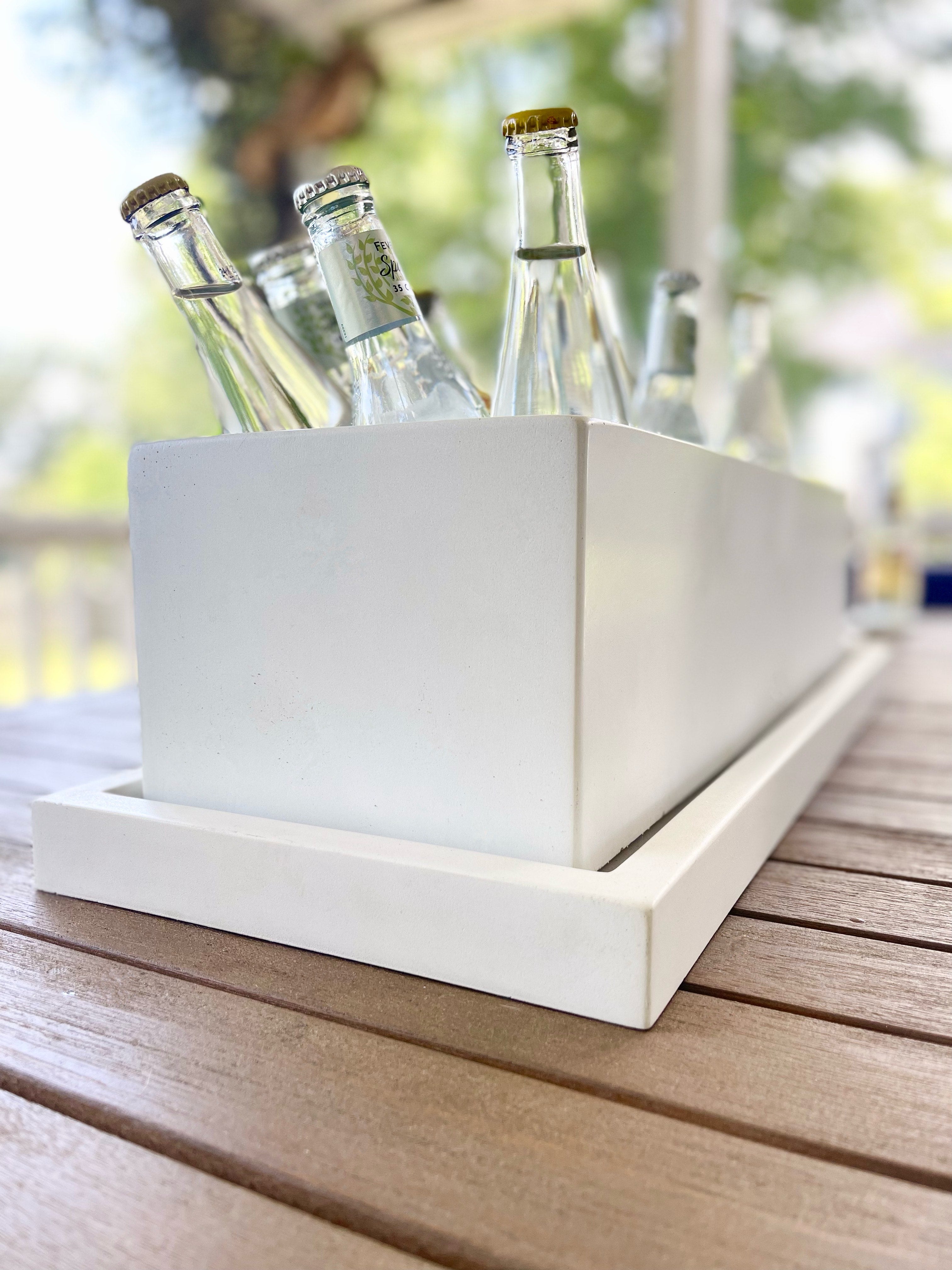 White rectangular ice bucket with bottles on a wooden surface outdoors. Henderson Garden Supply