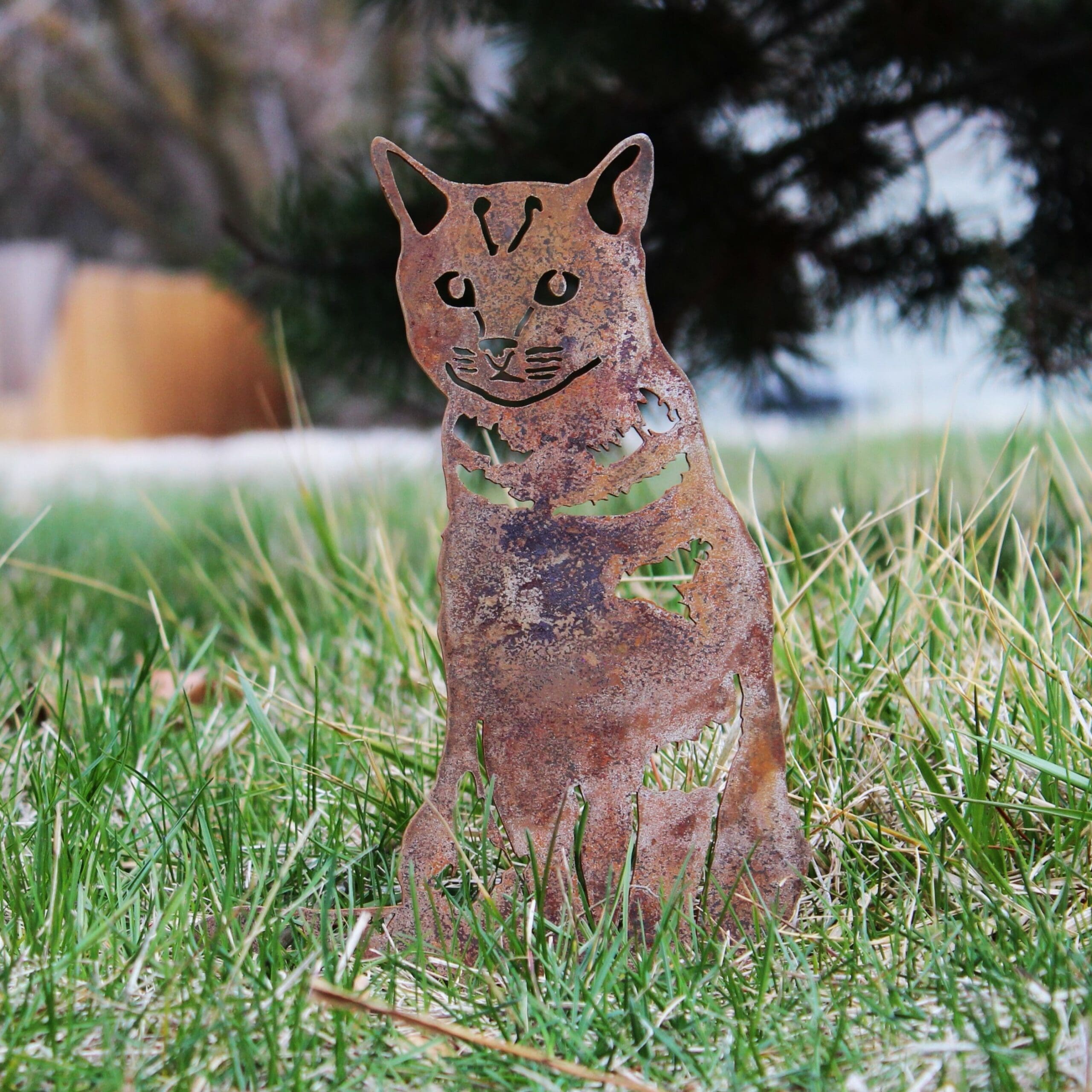 Rust-colored cat-shaped garden ornament in grass. Henderson Garden Supply