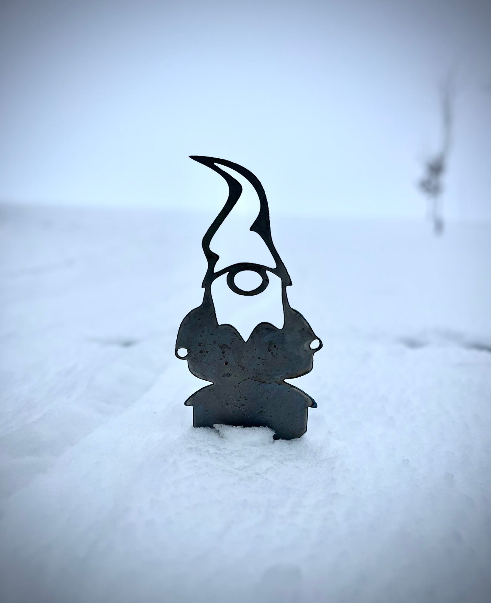 Metal gnome decoration on a snowy ground. Henderson Garden Supply