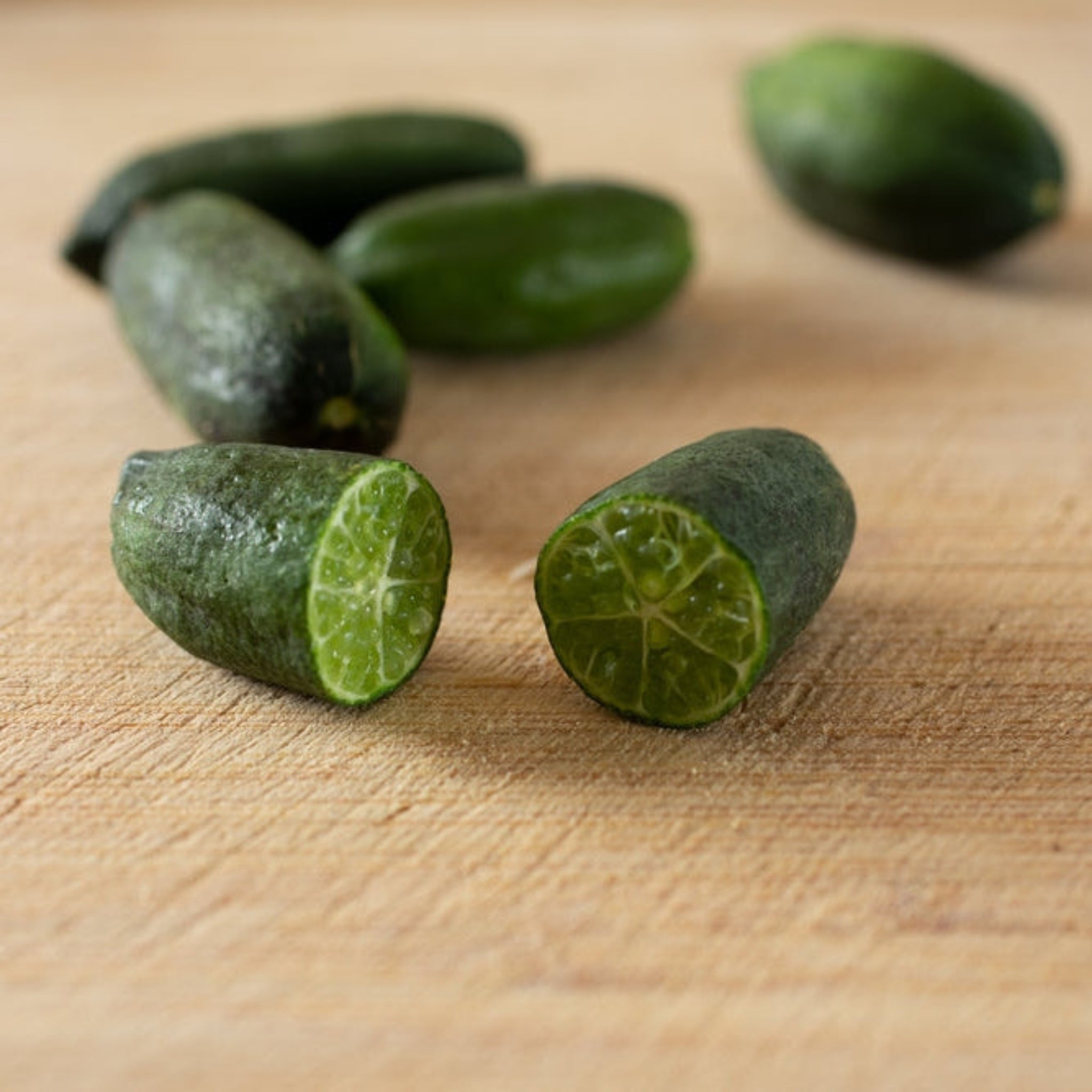 Green fruits, one cut in half, on a wooden surface. Henderson Garden Supply