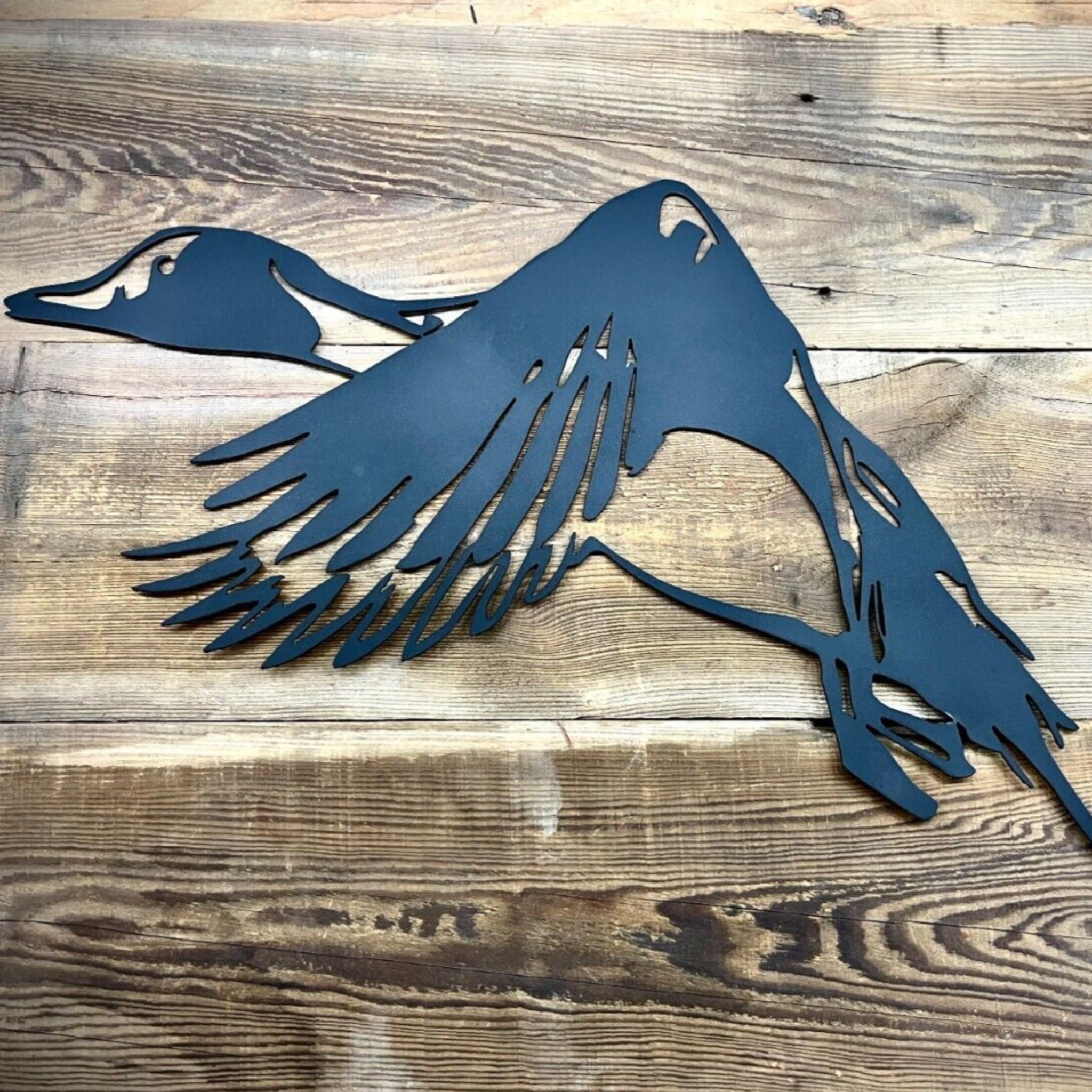 Metal duck sculpture on a wooden surface. Henderson Garden Supply