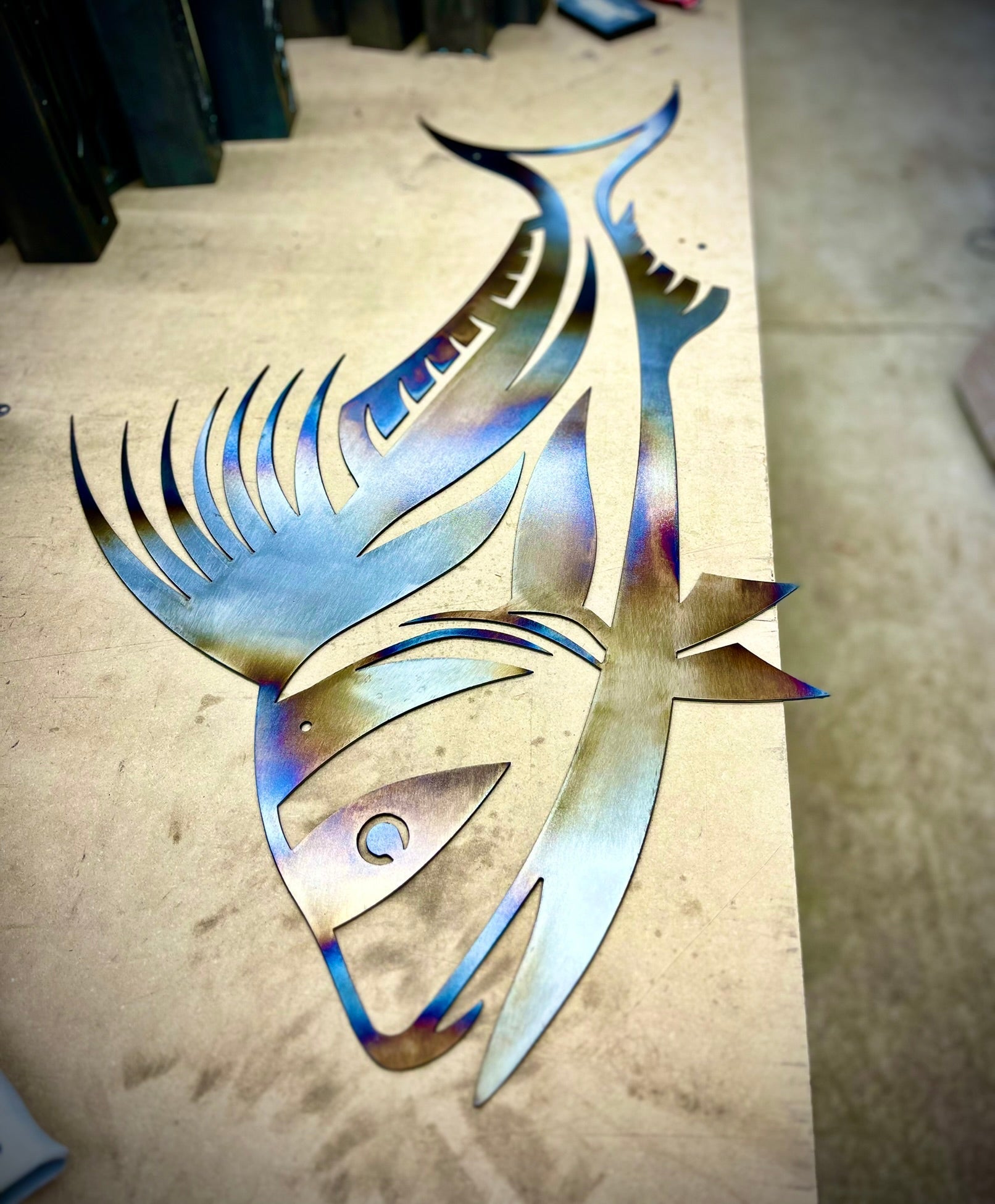 Metallic fish sculpture on a concrete floor. Henederson Garden Supply