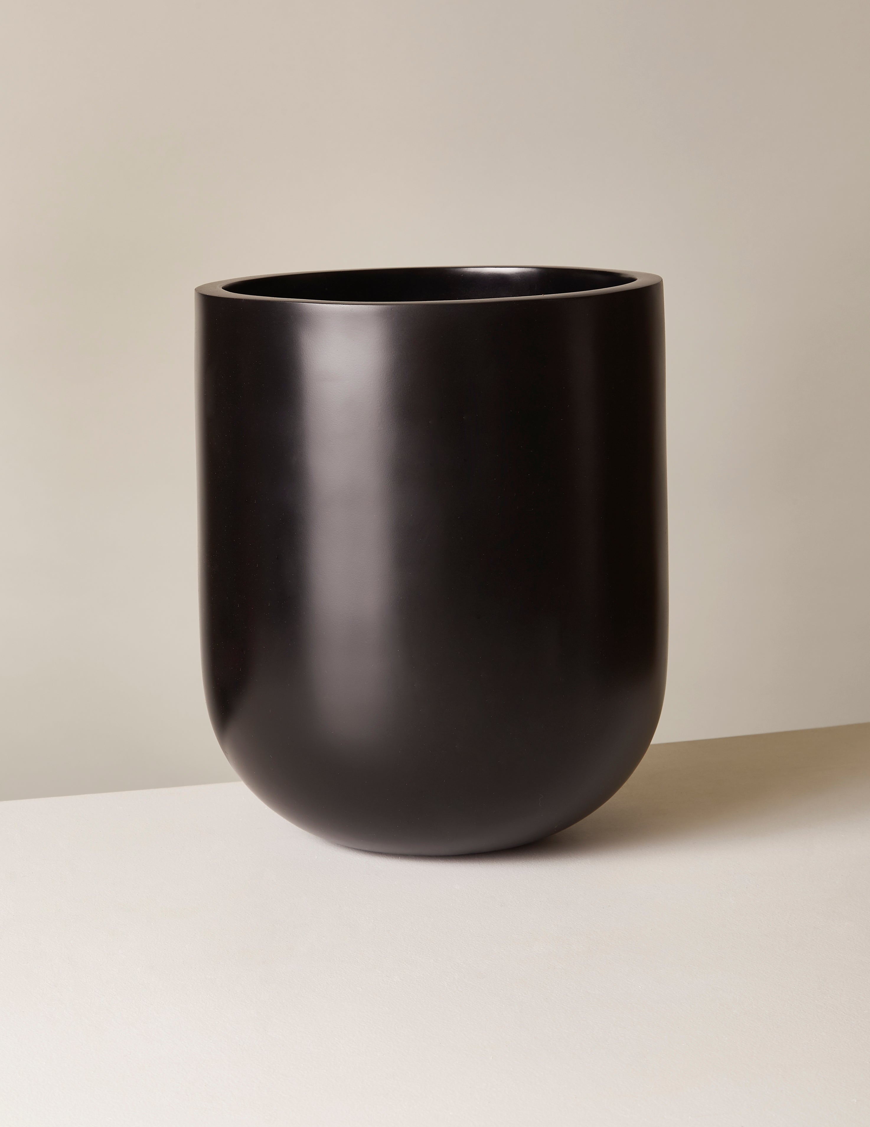 Black planter on a beige background. Henderson Garden Supply