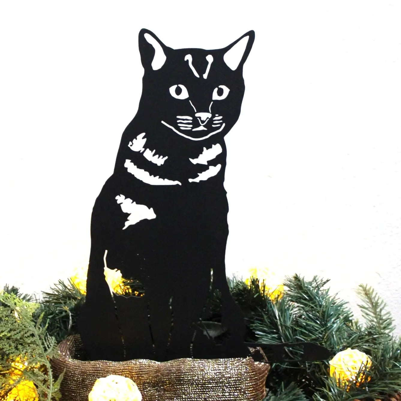 Black cat silhouette on a Christmas tree with greenery and gold ornaments.  Henderson Garden Supply