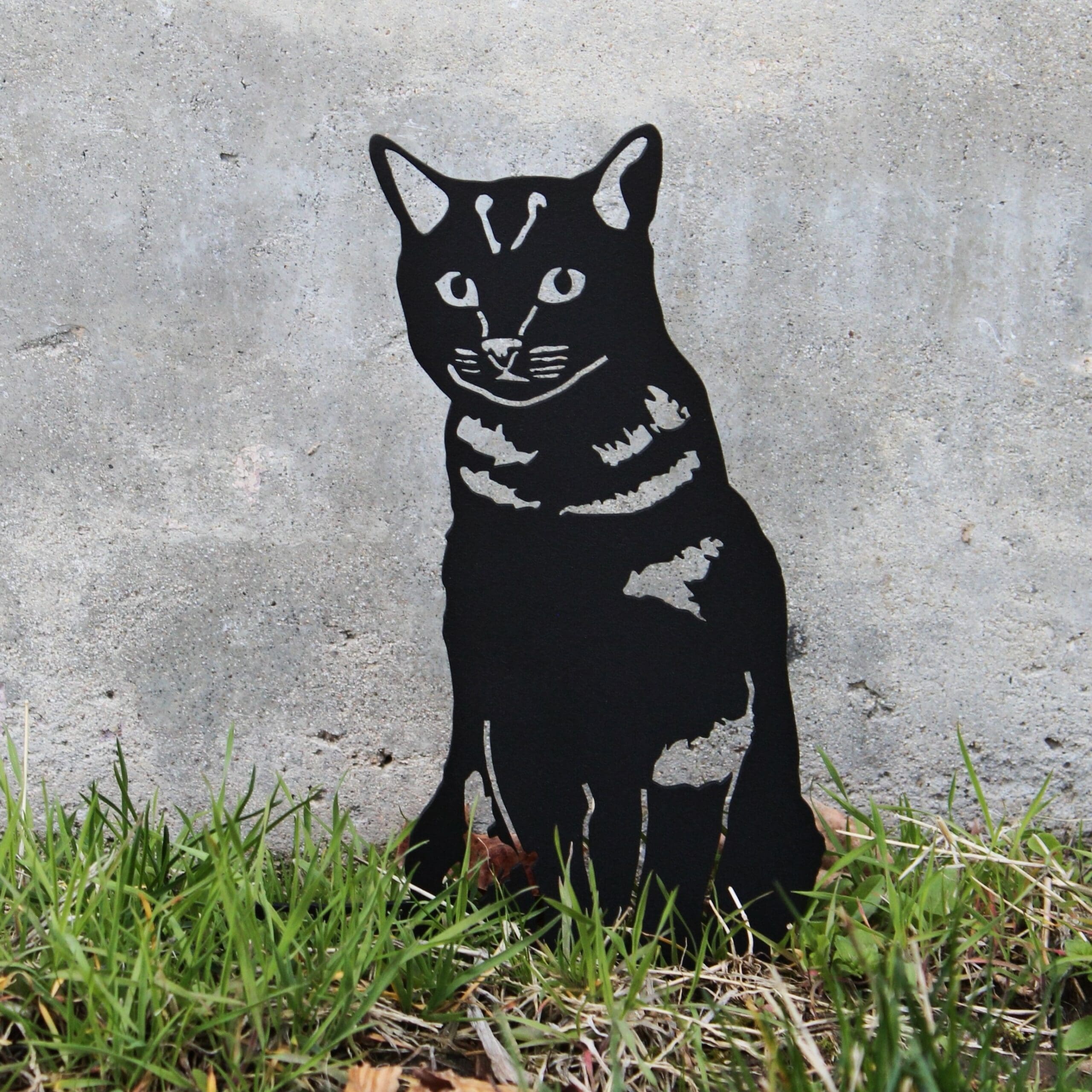 Black and white cat illustration on a concrete wall with grass at the base.  Henderson Garden Supply