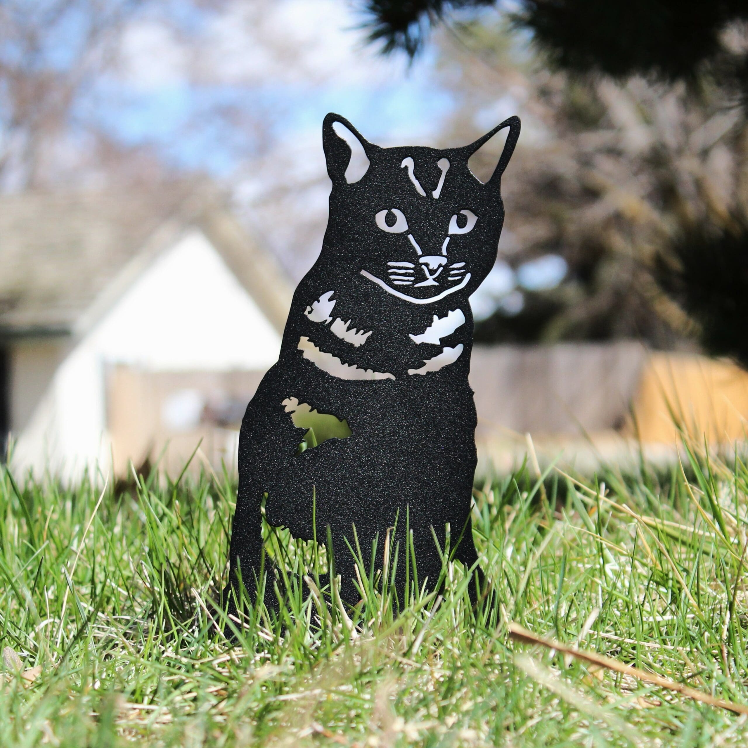 Black cat-shaped decorative object in a grassy outdoor setting.  Henderson Garden Supply