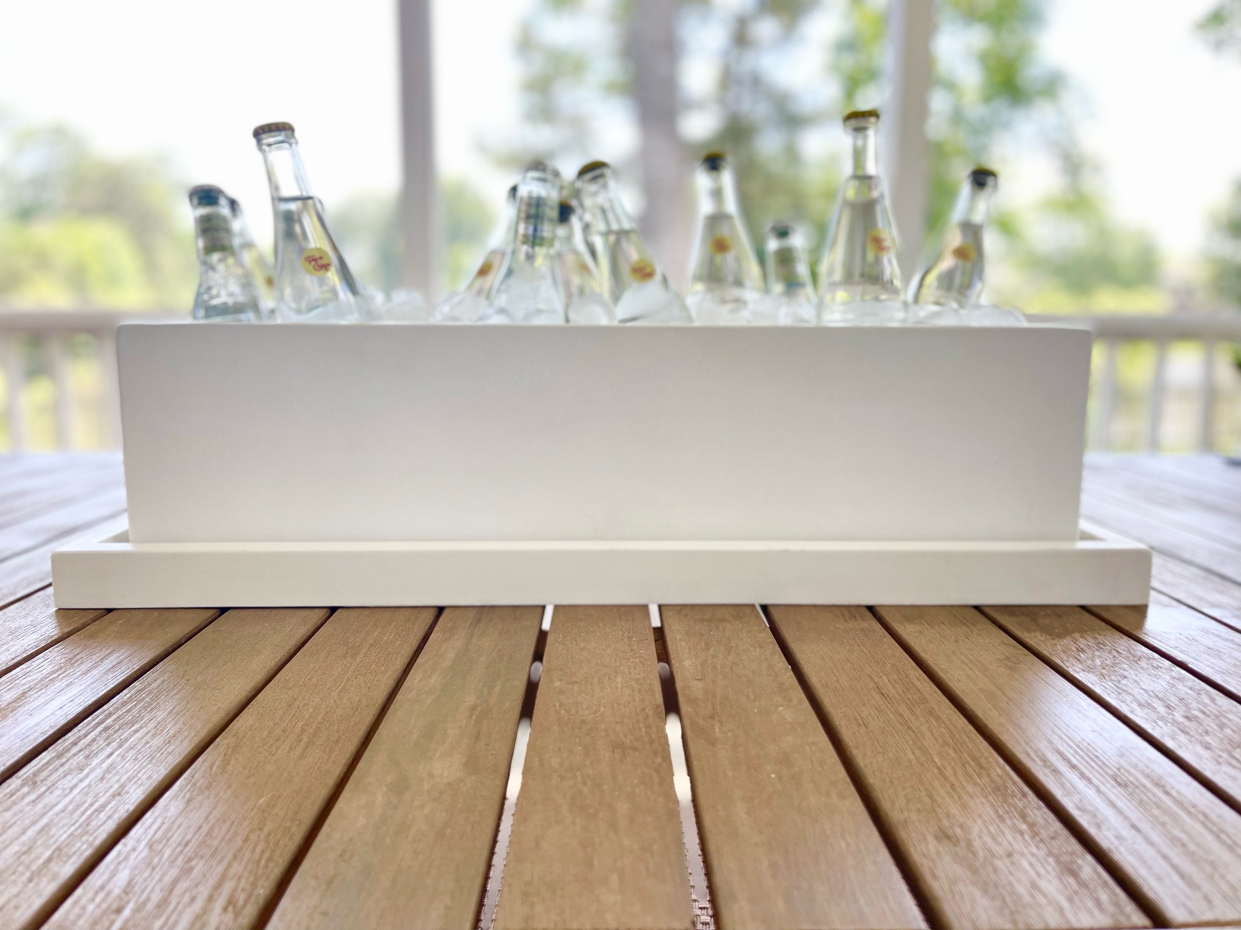 White outdoor cooler with bottles on a wooden deck.  Henderson Garden Supply