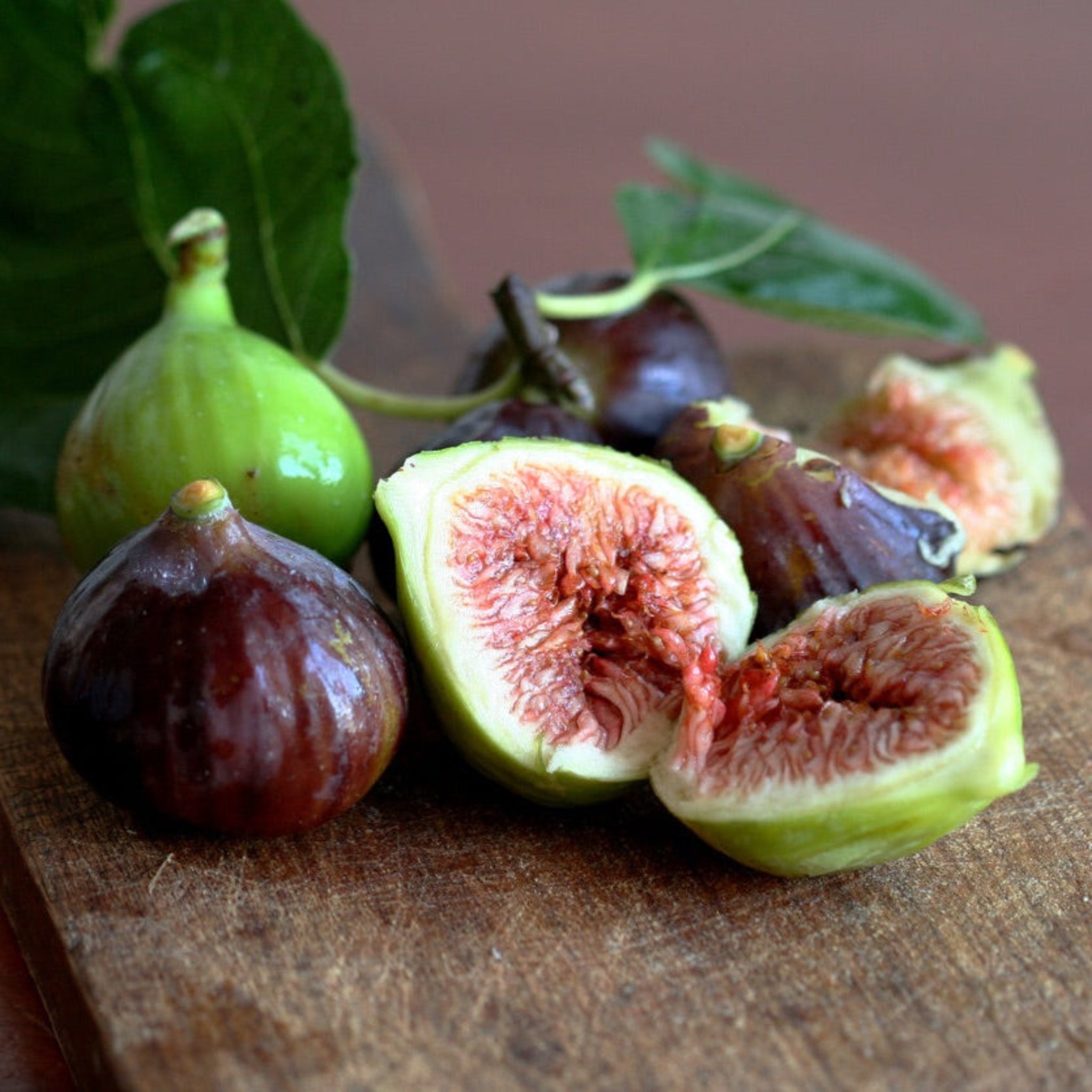 Figs on a wooden surface with one cut open to reveal the interior.  Henderson Garden Supply