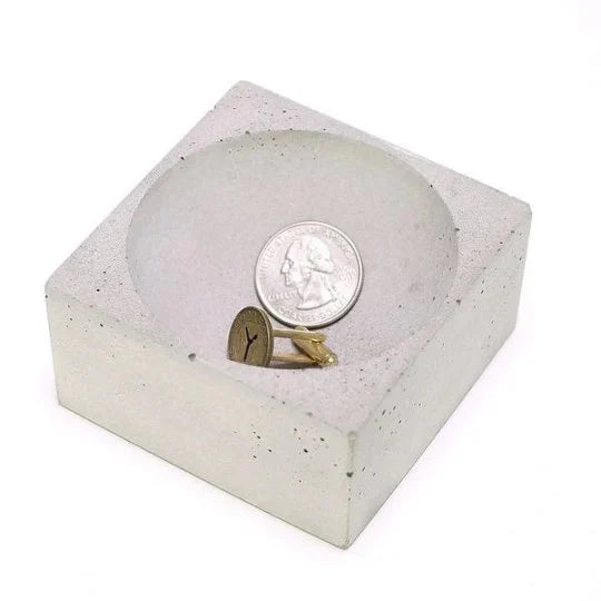 Concrete ring holder with a ring and quarter inside on a white background.  Henderson Garden Supply
