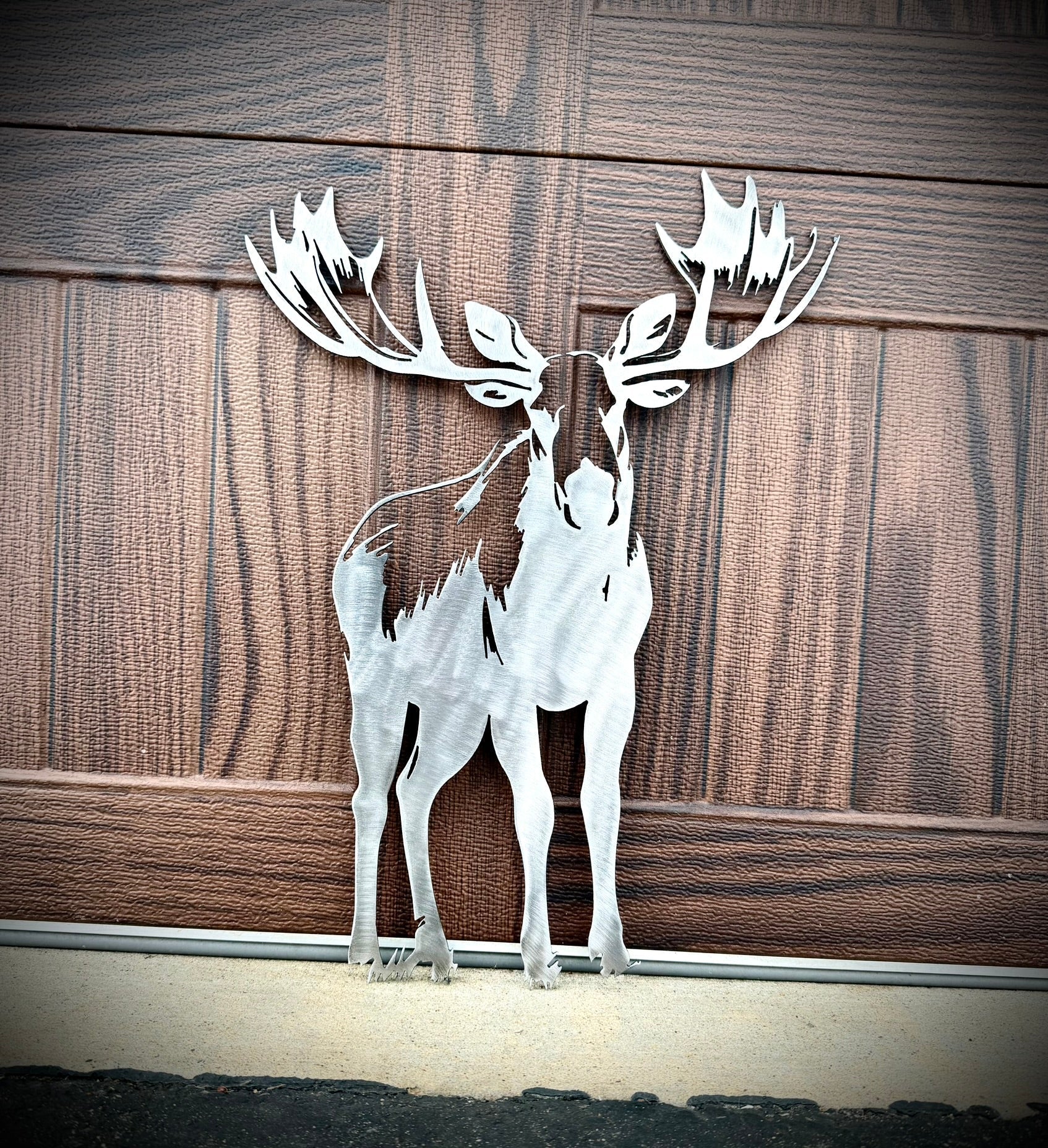 Metal deer sculpture on a wooden background.  Henderson Garden Supply