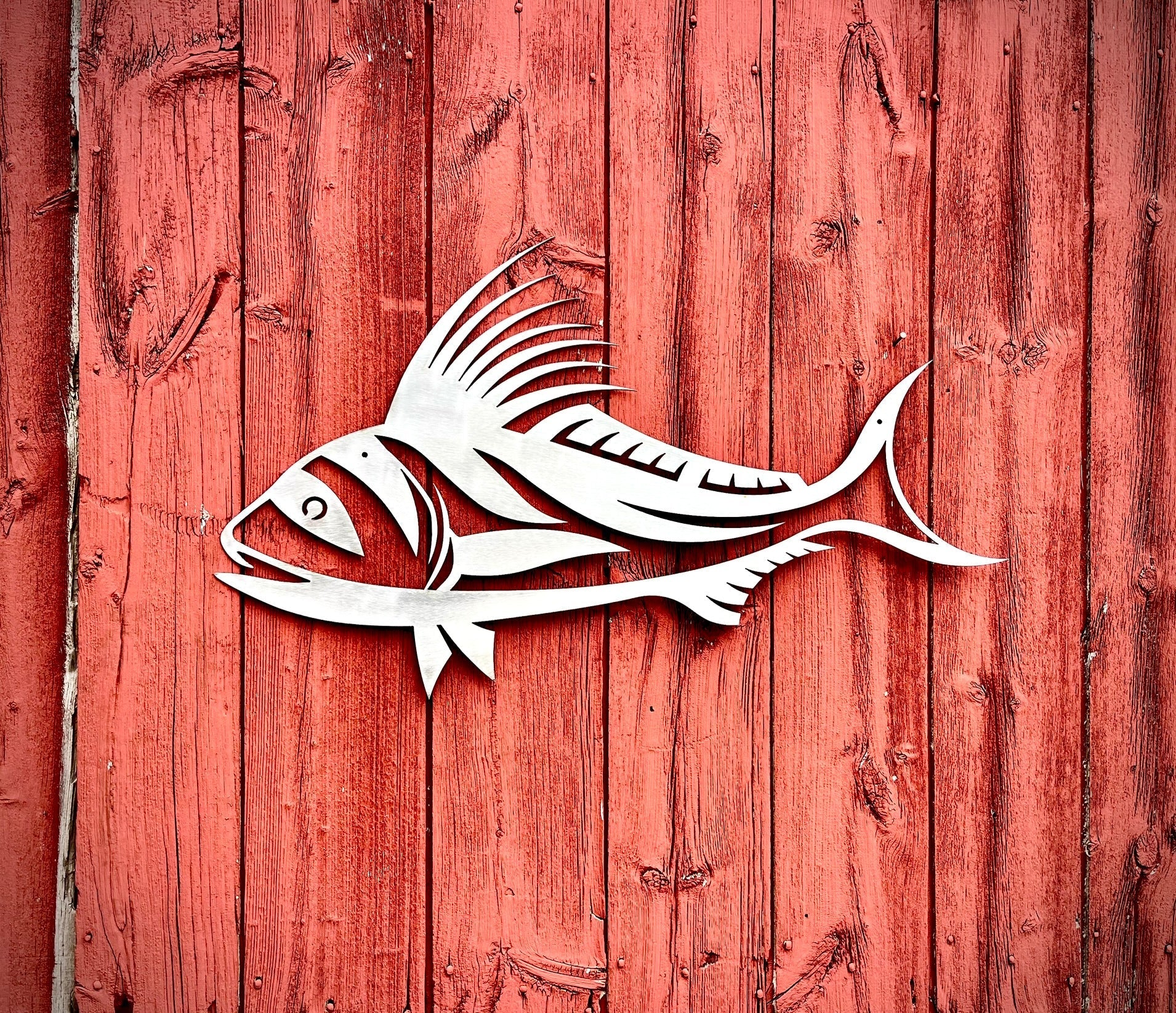 White fish design on a red wooden background.  Henderson Garden Supply