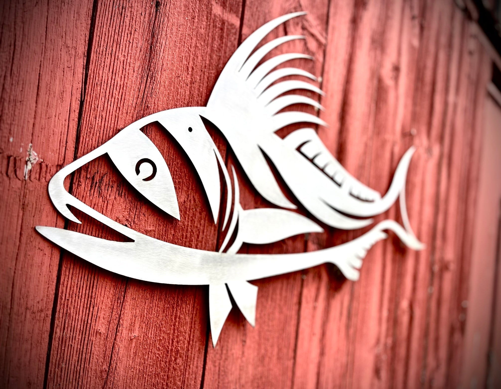 White fish cutout on a red wooden background.  Henderson Garden Supply