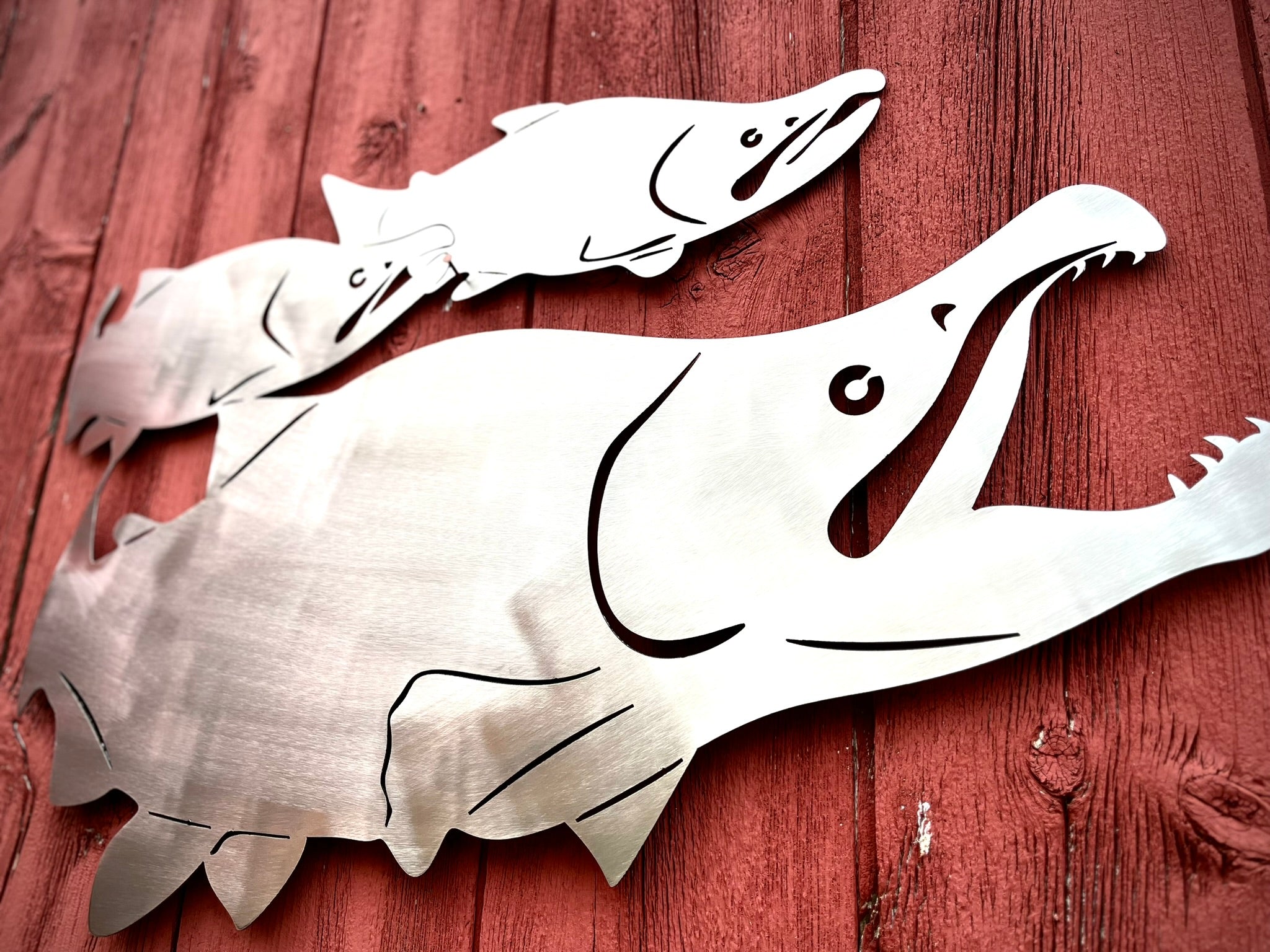 Metallic fish sculptures on a wooden surface.  Henderson Garden Supply
