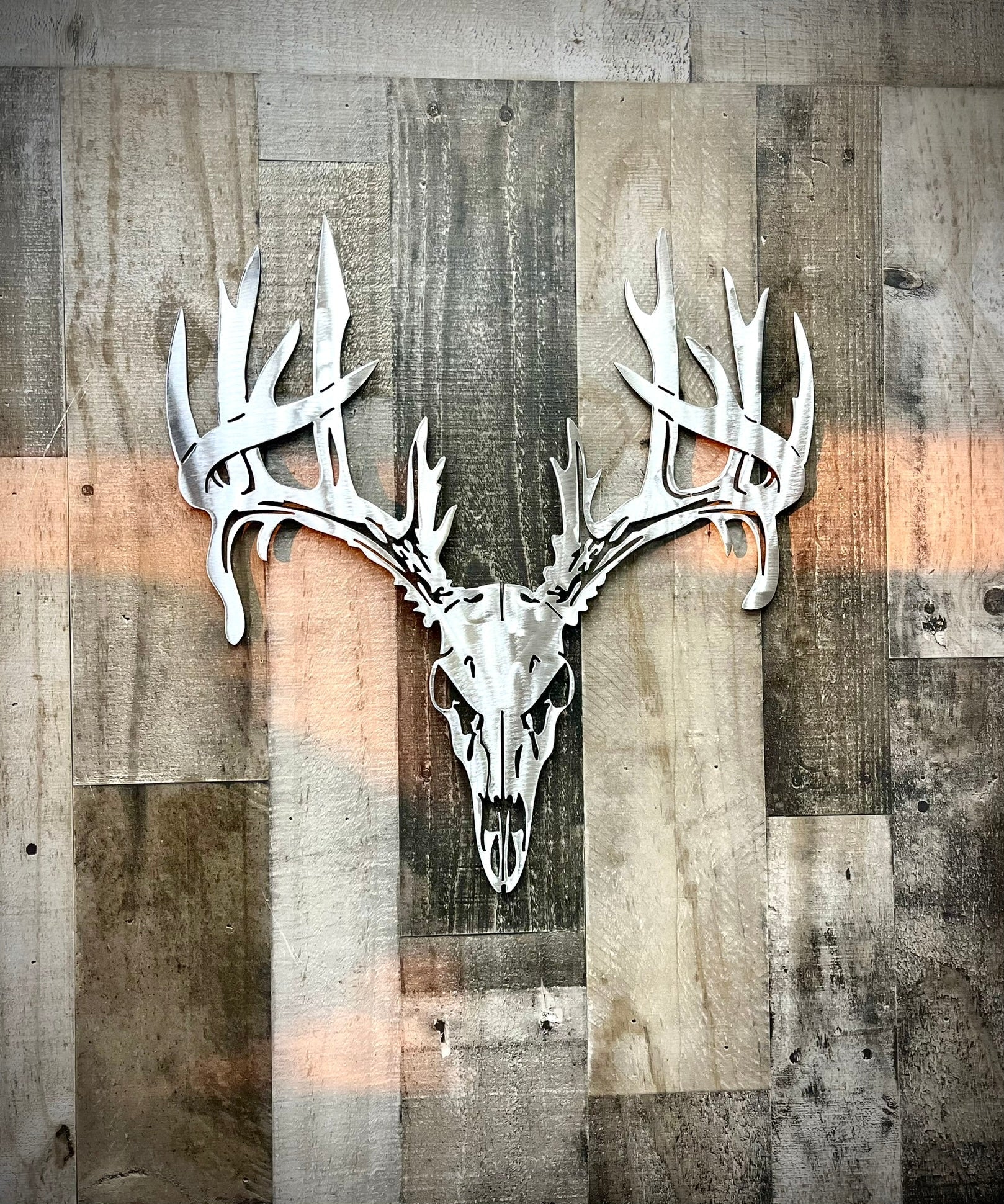 Metallic deer skull and antlers on a wooden panel background.  Henderson Garden Supply